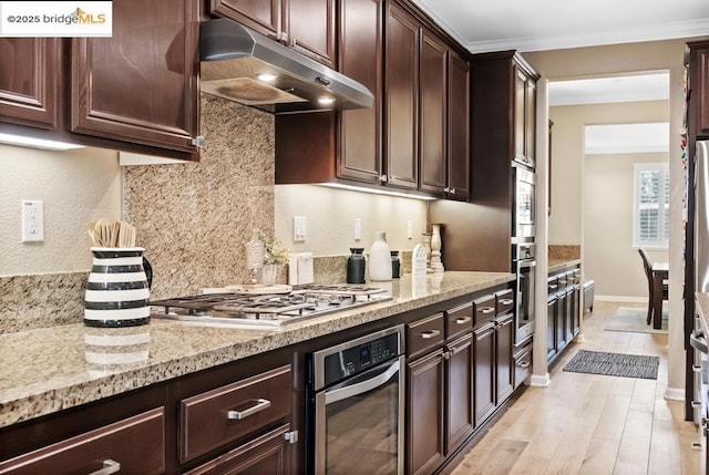 kitchen featuring appliances with stainless steel finishes, light stone counters, ornamental molding, light hardwood / wood-style floors, and decorative backsplash