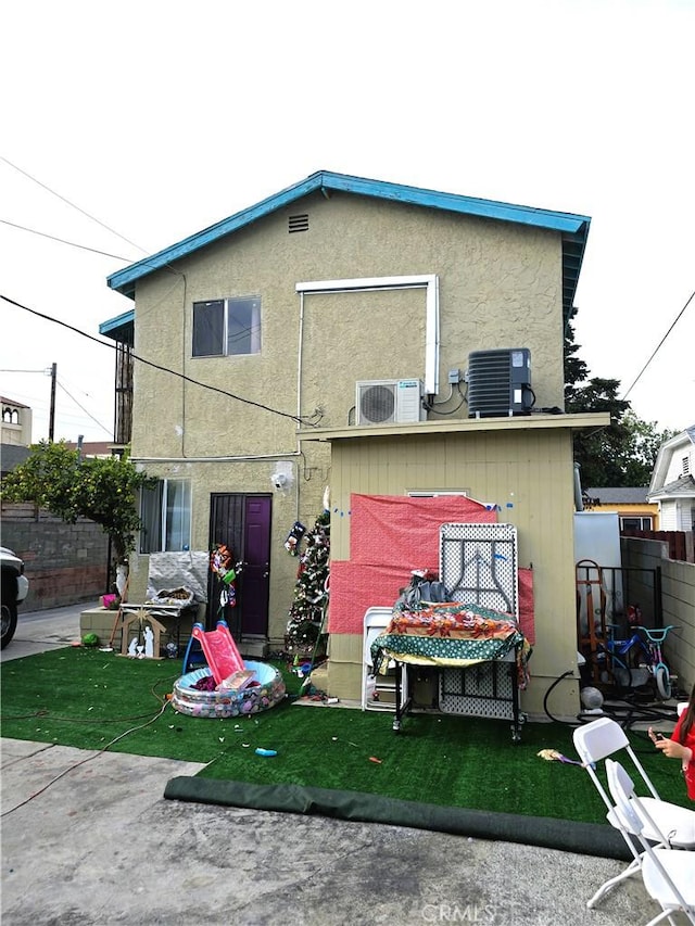 rear view of property with central AC unit, ac unit, and a yard