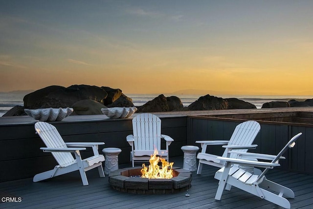 deck at dusk featuring a water view and a fire pit