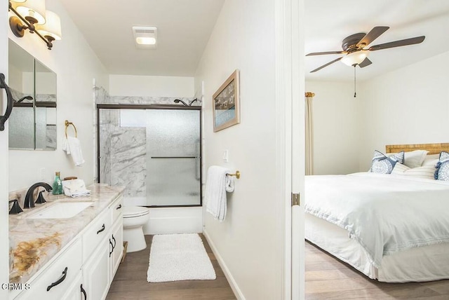 full bathroom featuring toilet, combined bath / shower with glass door, wood-type flooring, vanity, and ceiling fan