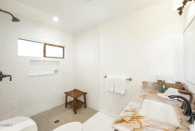 bathroom with a tile shower, vanity, and toilet