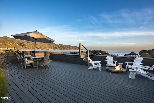 wooden terrace featuring a water and mountain view and a fire pit