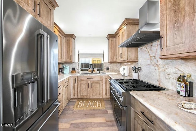 kitchen with hardwood / wood-style floors, tasteful backsplash, sink, premium appliances, and wall chimney range hood