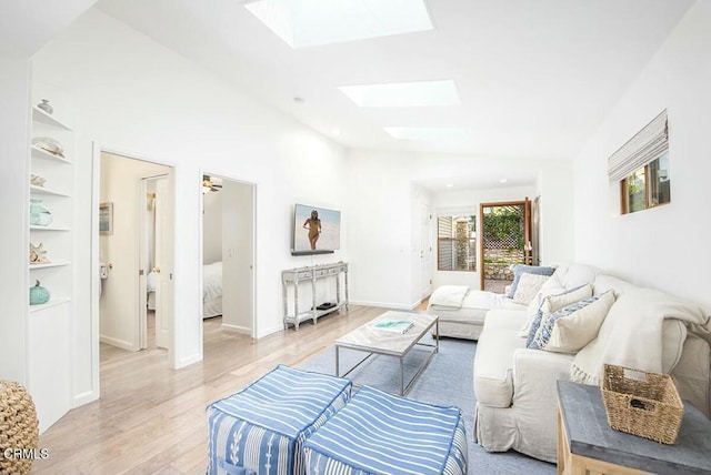 living room with light hardwood / wood-style flooring, built in features, and vaulted ceiling with skylight