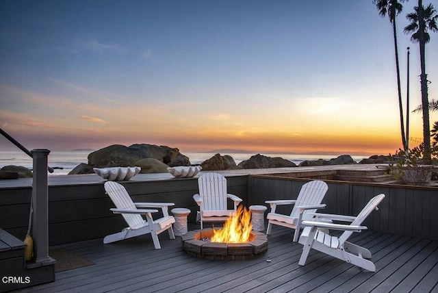 deck at dusk featuring a water view and a fire pit