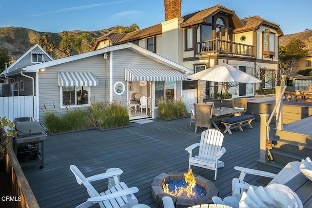 back of house with an outdoor fire pit and a deck with mountain view