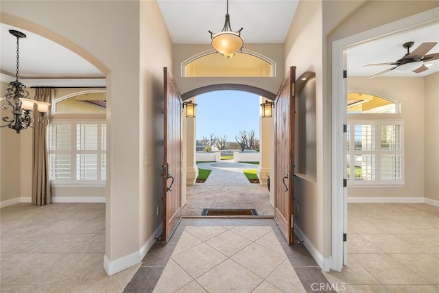 tiled entryway featuring ceiling fan with notable chandelier