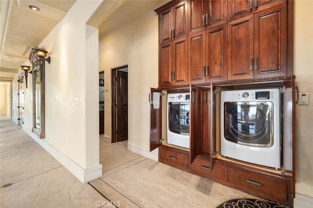 washroom featuring cabinet space, washer / dryer, and baseboards