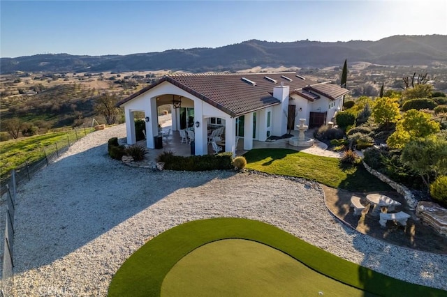 view of front of house featuring a patio, a tile roof, fence, and a mountain view