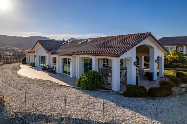 back of house with a mountain view and a patio area