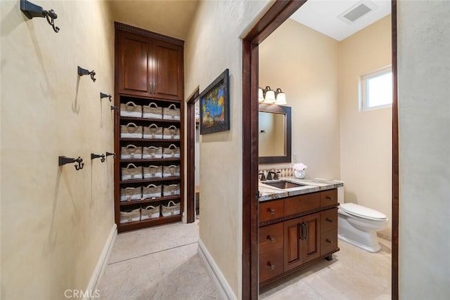 bathroom with toilet, vanity, visible vents, and baseboards