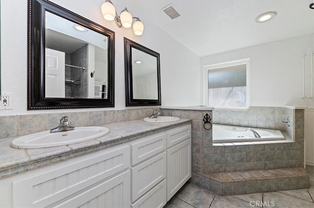 bathroom featuring a relaxing tiled tub, vanity, and tile patterned flooring