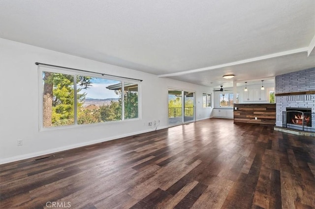 unfurnished living room featuring dark wood-type flooring, ceiling fan, and a fireplace