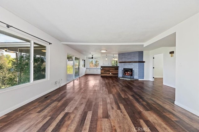 unfurnished living room featuring ceiling fan, a fireplace, and dark hardwood / wood-style flooring