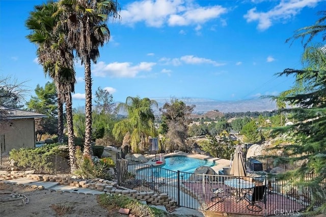 view of swimming pool with a hot tub, a mountain view, and a patio area