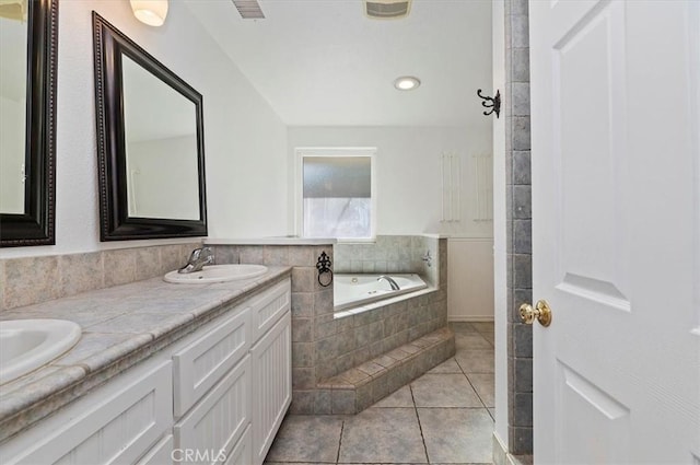 bathroom featuring vanity, tile patterned flooring, and tiled tub