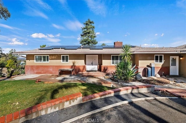 single story home with a patio area, a front lawn, and solar panels