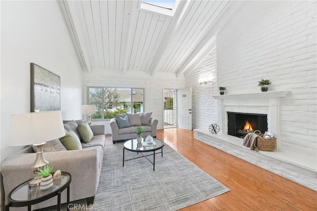 living room with a fireplace, lofted ceiling with skylight, and wood-type flooring