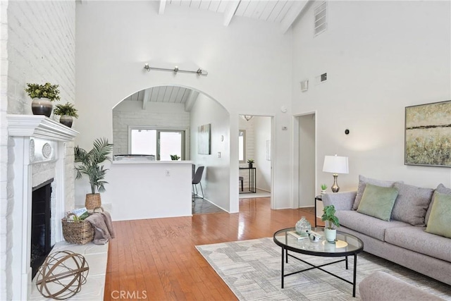 living room with a towering ceiling, wood-type flooring, and beam ceiling