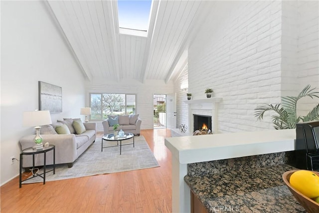 living room featuring vaulted ceiling with skylight, wood ceiling, and light hardwood / wood-style flooring