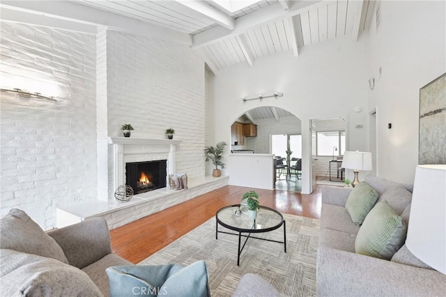 living room with beamed ceiling, high vaulted ceiling, and light hardwood / wood-style floors