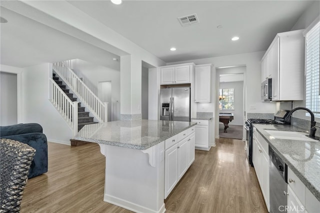 kitchen featuring white cabinetry, appliances with stainless steel finishes, a kitchen bar, and sink