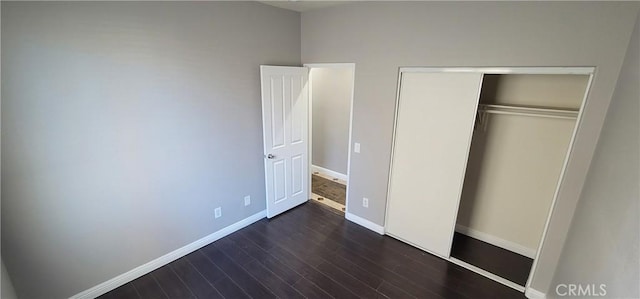 unfurnished bedroom with dark wood-type flooring and a closet