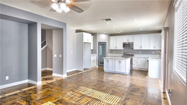 kitchen featuring sink, ceiling fan, stainless steel appliances, a center island, and white cabinets