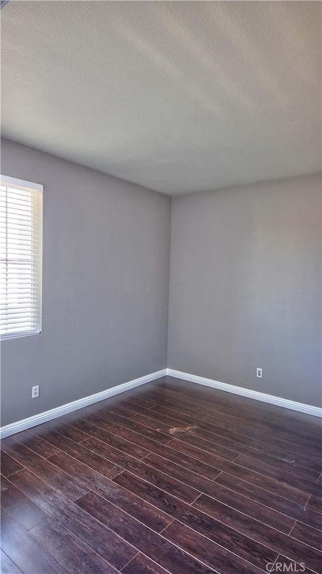 spare room with dark hardwood / wood-style floors and a textured ceiling