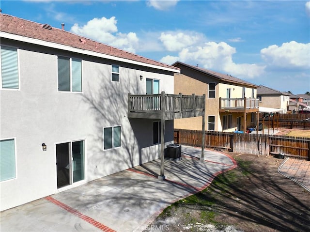 back of property with a balcony, a patio area, and central air condition unit