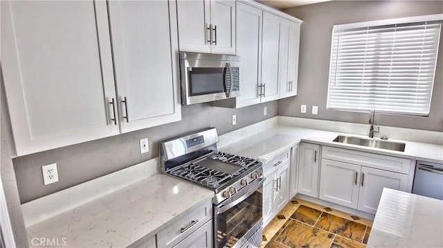 kitchen with appliances with stainless steel finishes, light stone countertops, and sink