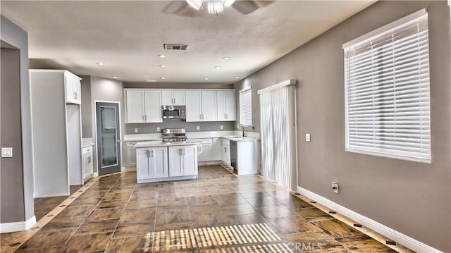 kitchen with stainless steel appliances, plenty of natural light, sink, and white cabinets