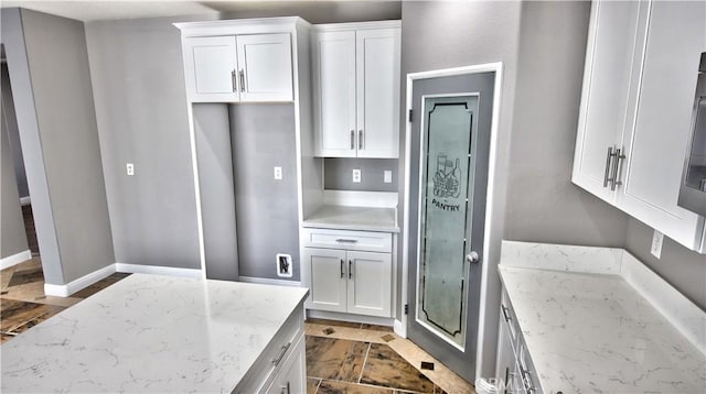 kitchen featuring white cabinetry and light stone countertops