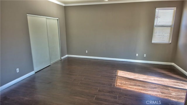 unfurnished bedroom with a closet, crown molding, and dark hardwood / wood-style floors