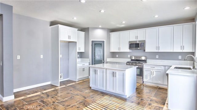 kitchen with white cabinetry, sink, stainless steel appliances, and a kitchen island