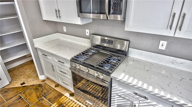 kitchen with stainless steel appliances, light stone countertops, and white cabinets