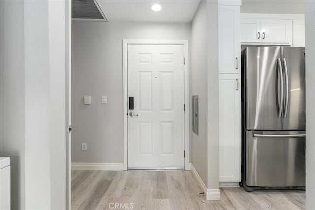 kitchen with white cabinetry, stainless steel fridge, and light hardwood / wood-style flooring