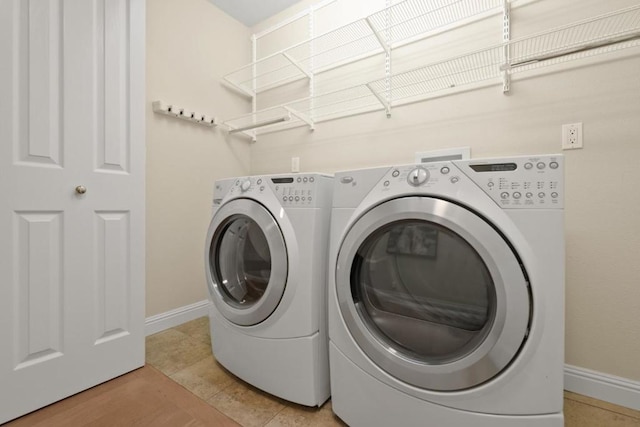 clothes washing area featuring light tile patterned flooring and separate washer and dryer