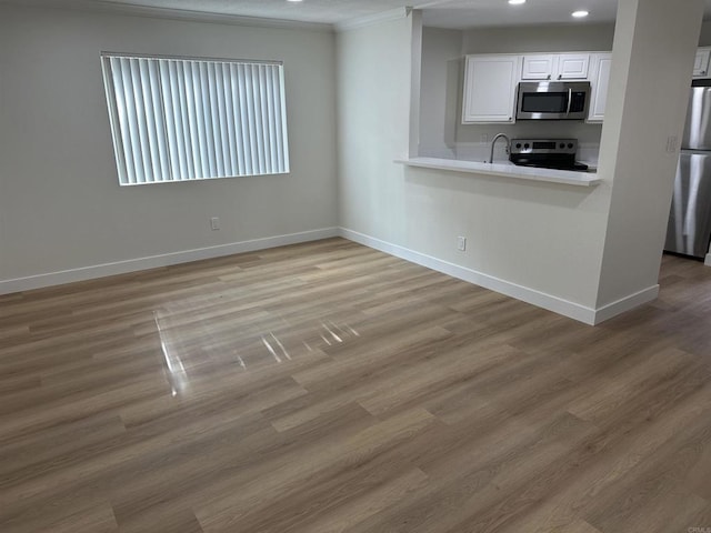 kitchen featuring stainless steel appliances, white cabinetry, sink, and light hardwood / wood-style floors