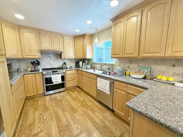 kitchen featuring appliances with stainless steel finishes, decorative light fixtures, backsplash, light brown cabinets, and light hardwood / wood-style flooring