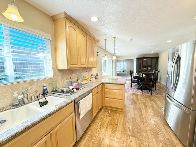 kitchen featuring pendant lighting, sink, appliances with stainless steel finishes, kitchen peninsula, and light brown cabinets