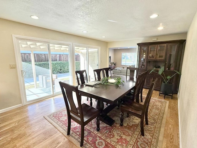 dining area with a textured ceiling and light hardwood / wood-style flooring