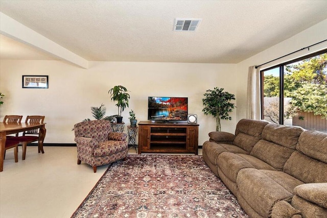 living room featuring beam ceiling, a textured ceiling, and concrete floors