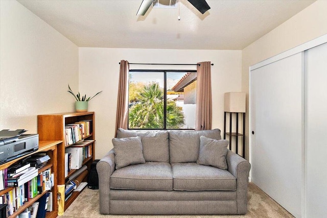 living area with ceiling fan and light carpet