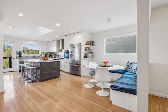 kitchen featuring white cabinetry, hanging light fixtures, appliances with stainless steel finishes, a kitchen island, and breakfast area