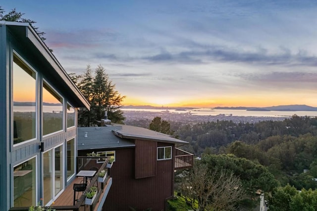 property exterior at dusk featuring a water and mountain view and a balcony