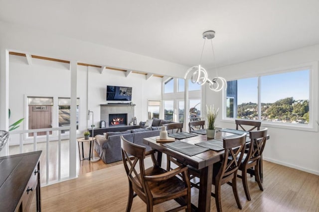 dining room with a wealth of natural light, a notable chandelier, beam ceiling, and light hardwood / wood-style flooring