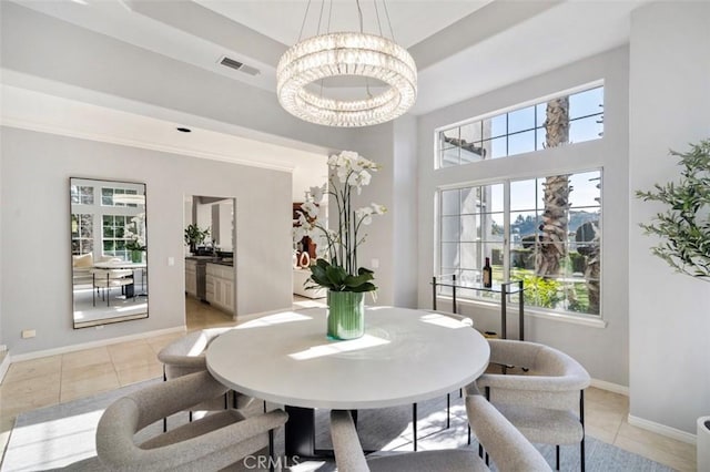 dining space with light tile patterned floors, plenty of natural light, a raised ceiling, and a chandelier