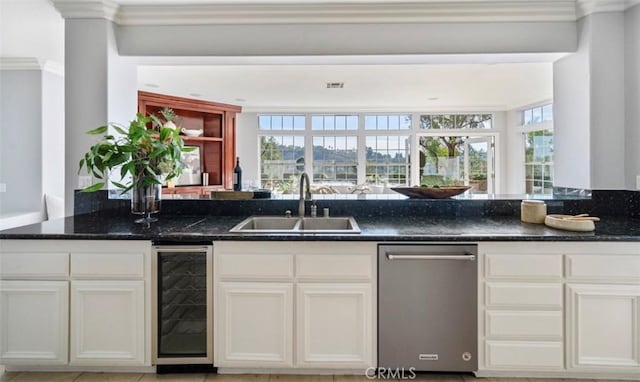 kitchen featuring dark stone countertops, sink, crown molding, and beverage cooler