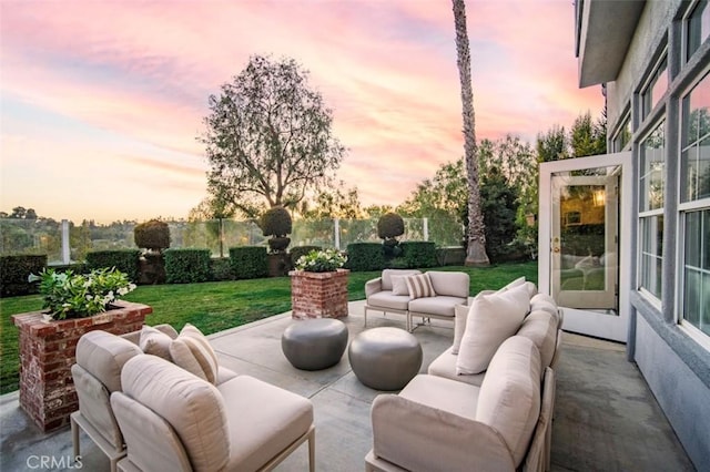 patio terrace at dusk with an outdoor living space and a yard